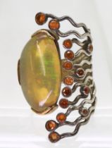 A yellow and white metal handmade bespoke designer ring, set with a large colourful jelly opal and