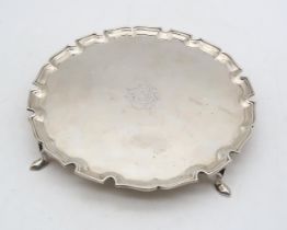A George V silver waiter, London 1928, of circular form with a chippendale-style border, on four pad