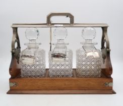 A three bottle tantalus, with hobnail cut bottles and one silver 'Brandy' decanter label, an EPNS '