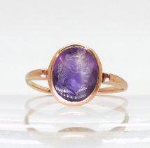 A rose coloured metal signet ring set with an intaglio carved amethyst, depicting a maiden, finger