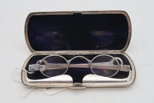 A cased pair of silver spectacles, the stamped sterling case with hammered decoration and a vacant