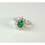 An 18ct white gold emerald and diamond oval cluster ring