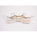A two handled silver sugar bowl and two silver cream jugs