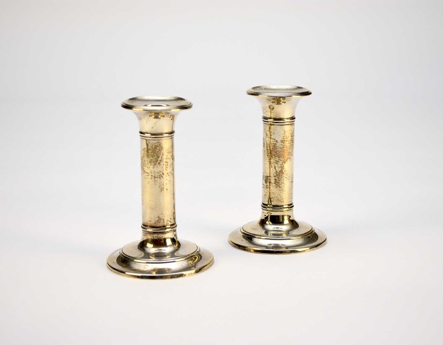 A pair of Edwardian short silver candlesticks