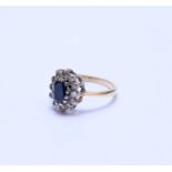 A yellow metal oval sapphire and diamond cluster ring