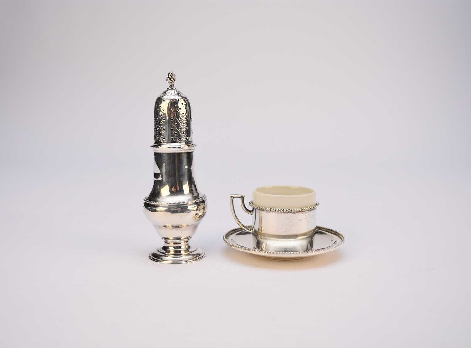 A George III silver caster and a silver cup and saucer