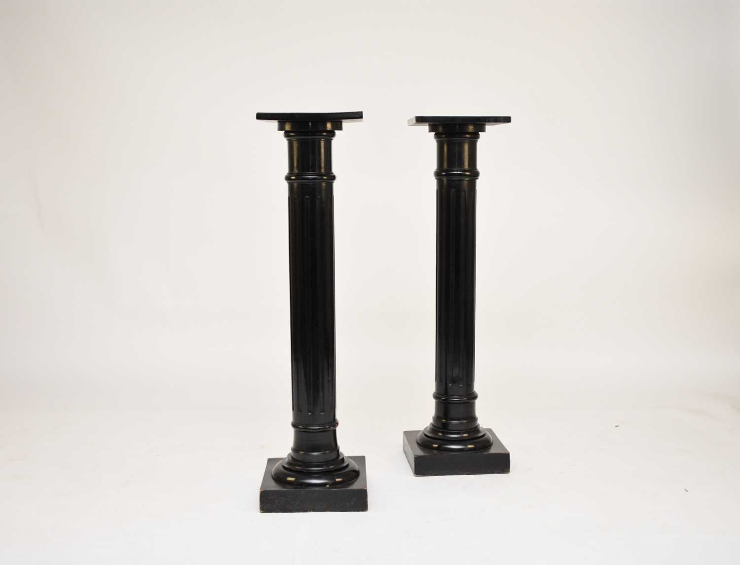 A pair of late Victorian ebonised wood torchere stands