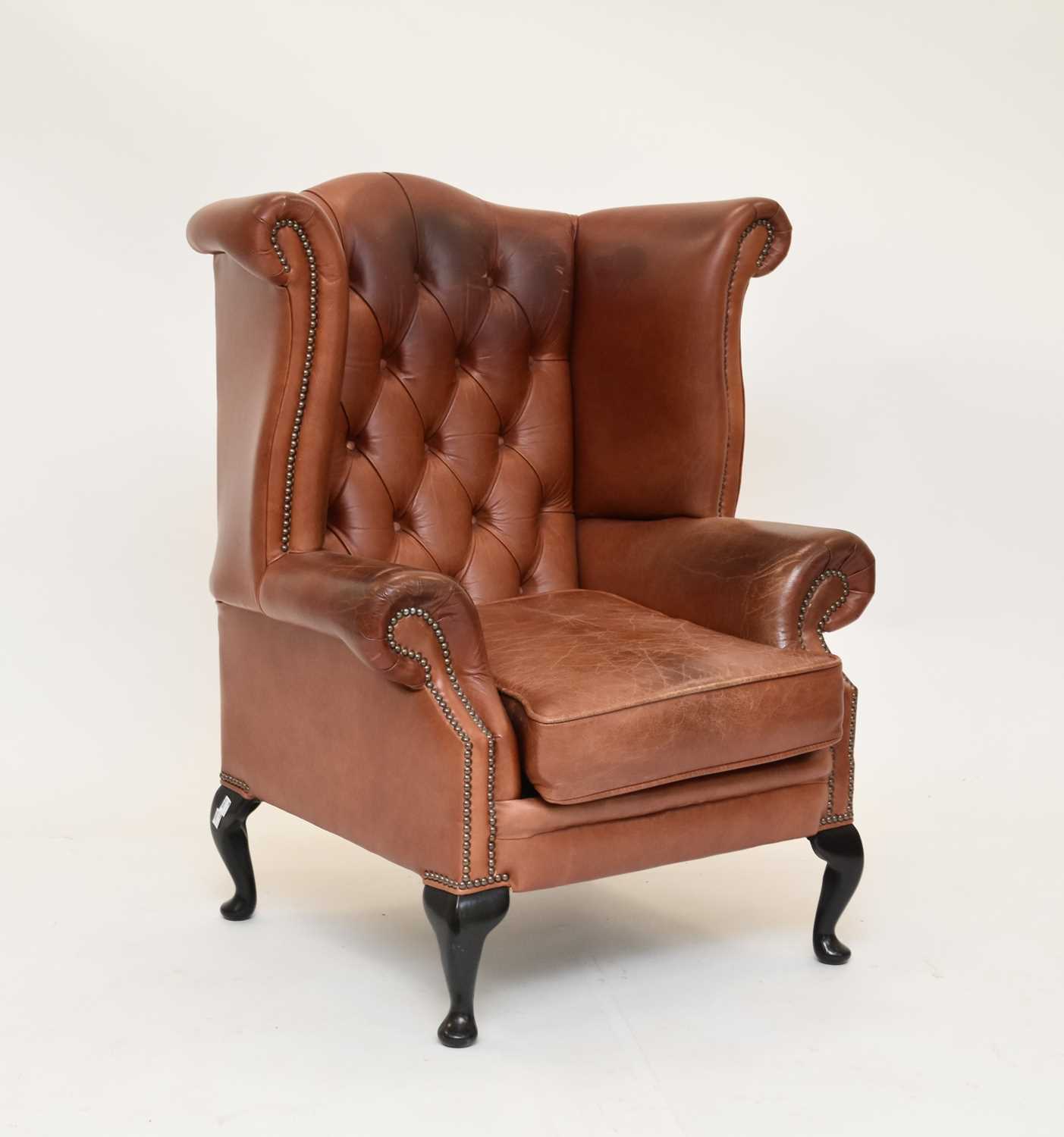 A reproduction tan leather wing armchair