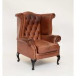 A reproduction tan leather wing armchair