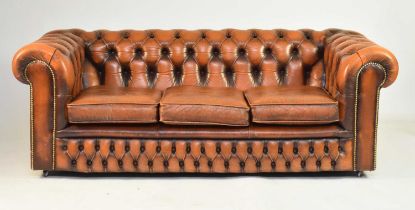 A tan leather Chesterfield suite of sofa and two armchairs