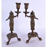 A PAIR OF 19TH CENTURY MIDDLE EASTERN INDIAN BRONZE CANDLESTICKS formed as deities holding aloft sco