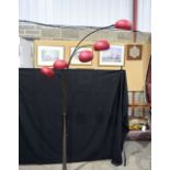 A contemporary five armed lampstand with red glass shades. Height 192cm.