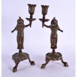 A PAIR OF 19TH CENTURY MIDDLE EASTERN INDIAN BRONZE CANDLESTICKS formed as deities holding aloft sco