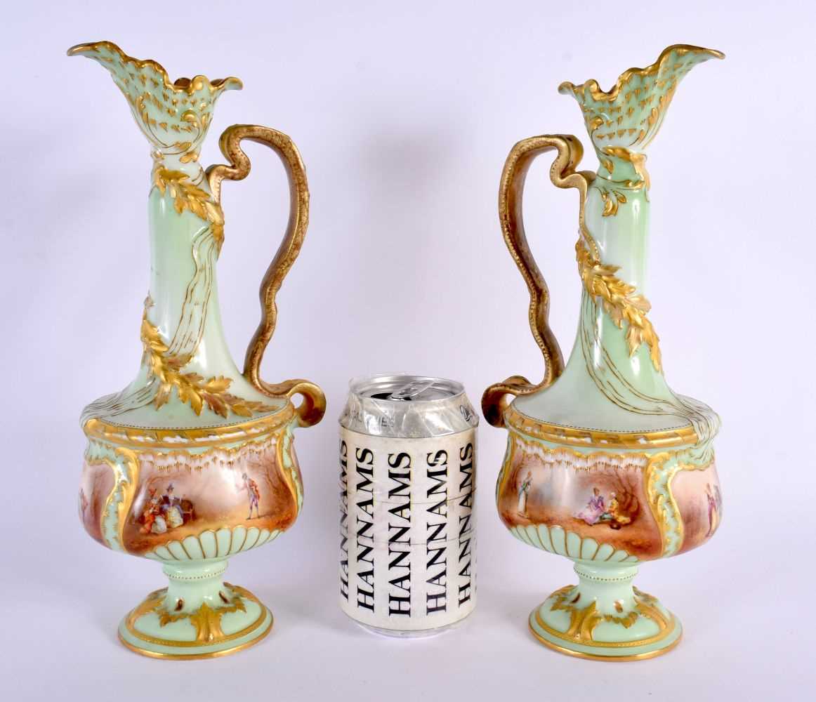 A PAIR OF ANTIQUE FRENCH LIMOGES PORCELAIN EWER painted with figures in a landscape upon a green