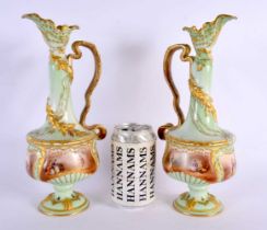 A PAIR OF ANTIQUE FRENCH LIMOGES PORCELAIN EWER painted with figures in a landscape upon a green