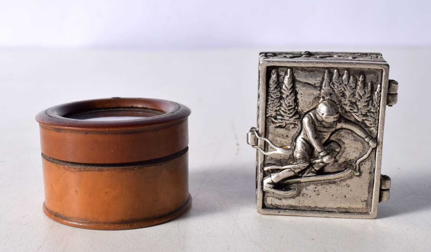 A small white metal Alpine Skier pill box together with a treen glass topped pill box 3 x 2 cm. (2)