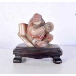 A Chinese carved soapstone figure of buddha, formed upon a stand. 12 cm x 10 cm.