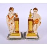 A PAIR OF LATE 18TH CENTURY ENGLISH CREAMWARE POTTERY FIGURES modelled resting upon columns. 12 cm