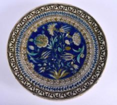 A 19TH CENTURY MIDDLE EASTERN FAIENCE TIN GLAZED IZNIK DISH painted with flowers and motifs. 26 cm