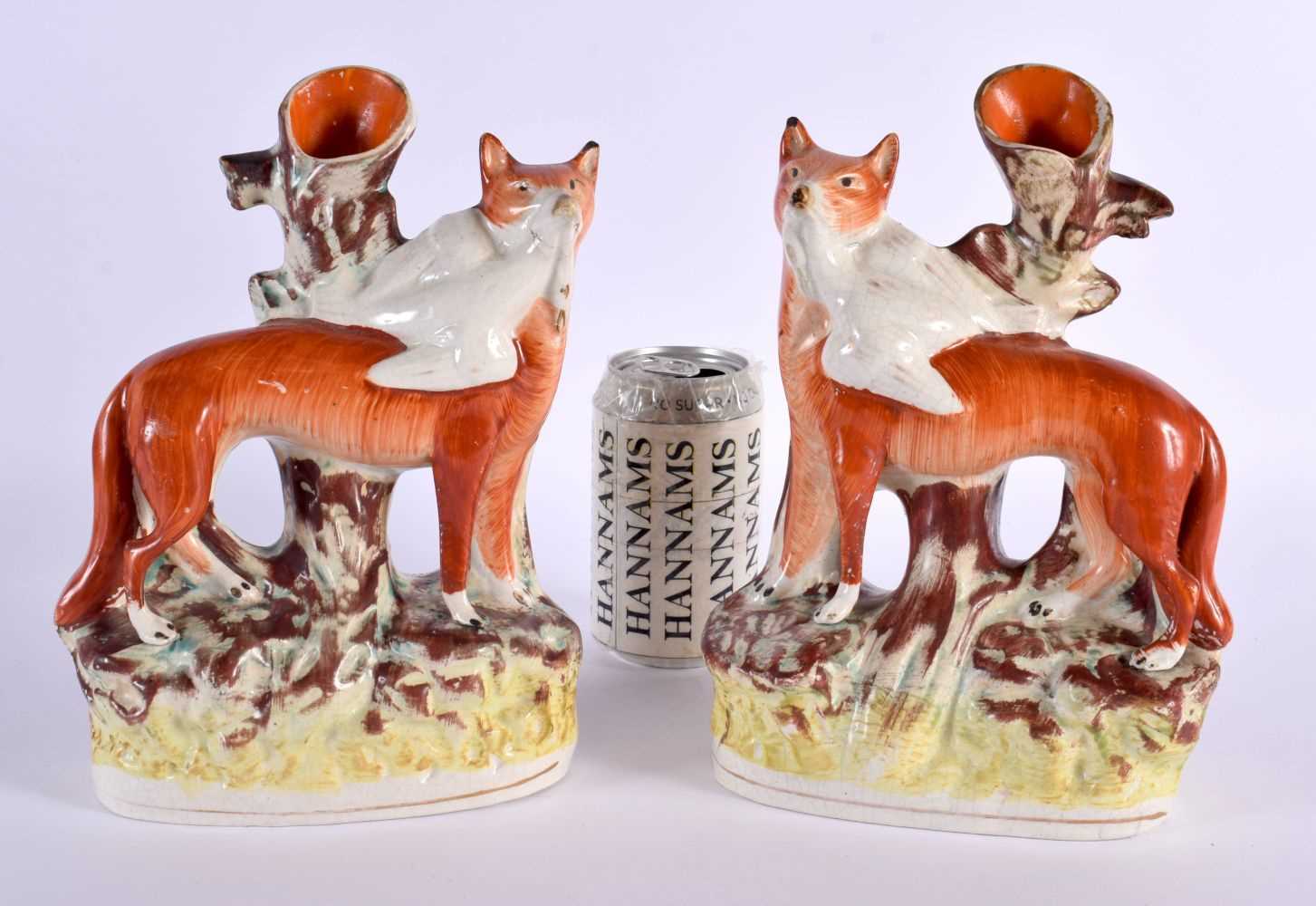 A LARGE PAIR OF 19TH CENTURY STAFFORDSHIRE FIGURES OF FOXES modelled holding game birds. 26 cm x