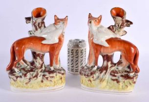 A LARGE PAIR OF 19TH CENTURY STAFFORDSHIRE FIGURES OF FOXES modelled holding game birds. 26 cm x