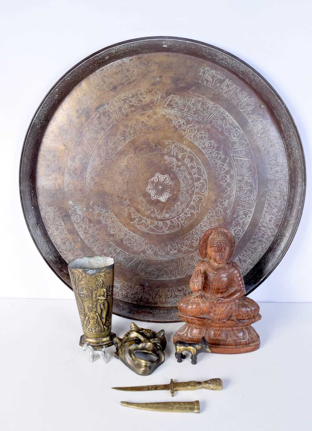 A large Egyptian copper charger together with other metal items and a South East Asian wooden Buddha