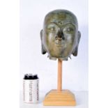 A Tibetan bronze head of Buddha, modelled upon a wooden stand. Bronze 23 x 16.5cm.