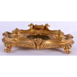 AN EARLY 19TH CENTURY FRENCH GILT BRONZE AND MARBLE DESK STAND of scrolling organic form, overlaid