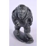 A NORTH AMERICAN INUIT CARVED STONE FIGURE OF A SEAL HUNTER modelled carrying a catch upon his back.