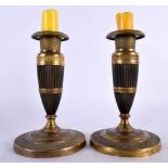 A PAIR OF EARLY 19TH CENTURY FRENCH EMPIRE TWO TONE BRONZE CANDLESTICKS formed as tapered ribbed