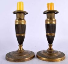 A PAIR OF EARLY 19TH CENTURY FRENCH EMPIRE TWO TONE BRONZE CANDLESTICKS formed as tapered ribbed