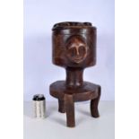 An African tribal carved wood food pot on stand with face mask handles, the lid is carved with a