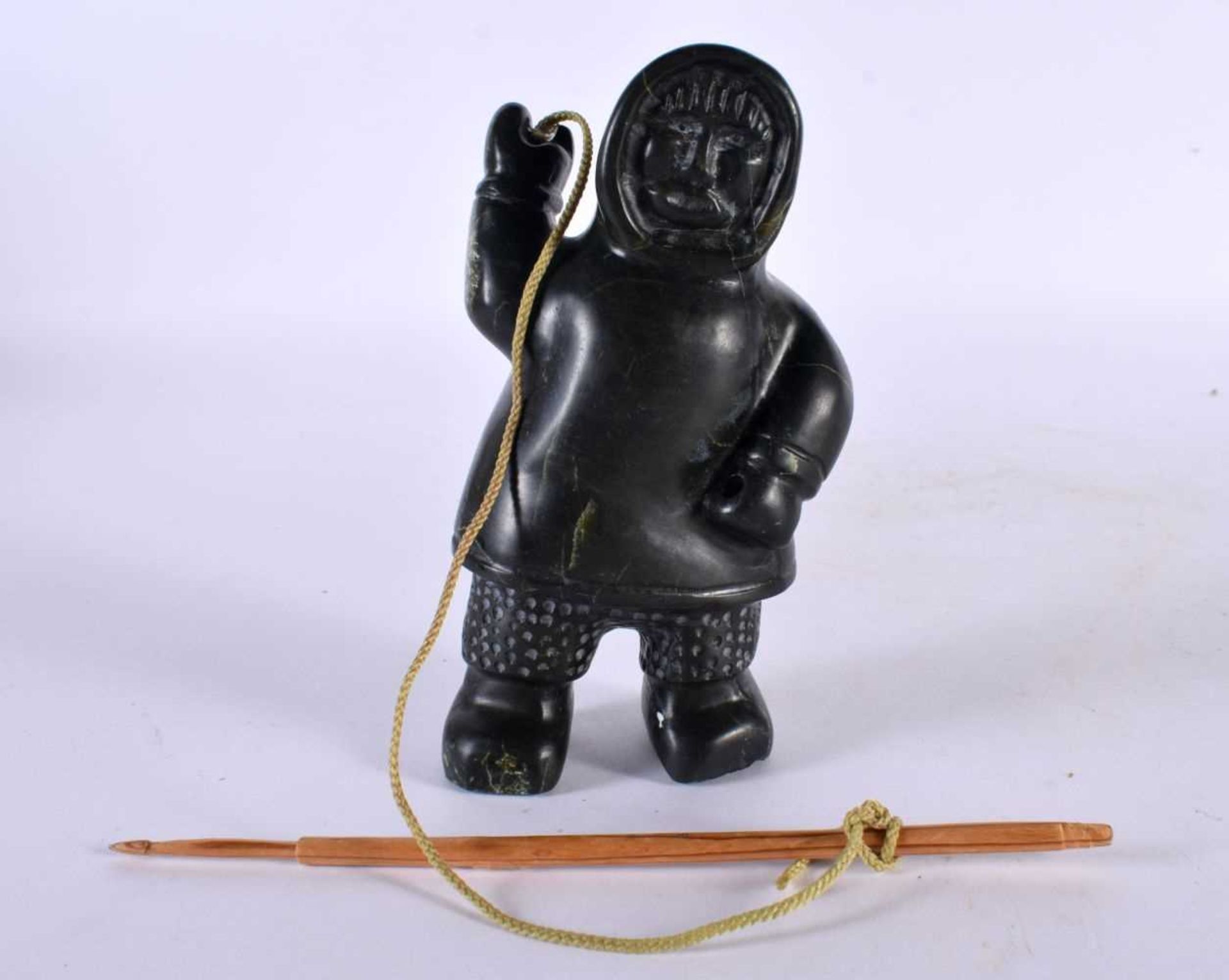 A NORTH AMERICAN CARVED JADE INUIT FIGURE OF AN ESKIMO SEAL HUNTER modelled holding a spear and