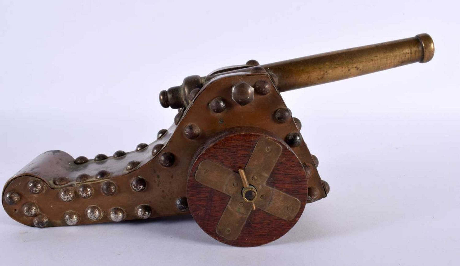 A 19TH CENTURY COUNTRY HOUSE BRONZE AND CARVED WOOD DESK CANNON upon revolving wheels. 27 cm wide.