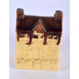 AN ANTIQUE TREACLE GLAZED POTTERY MONEY BOX formed as a house. 10 cm x 6 cm.