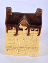 AN ANTIQUE TREACLE GLAZED POTTERY MONEY BOX formed as a house. 10 cm x 6 cm.