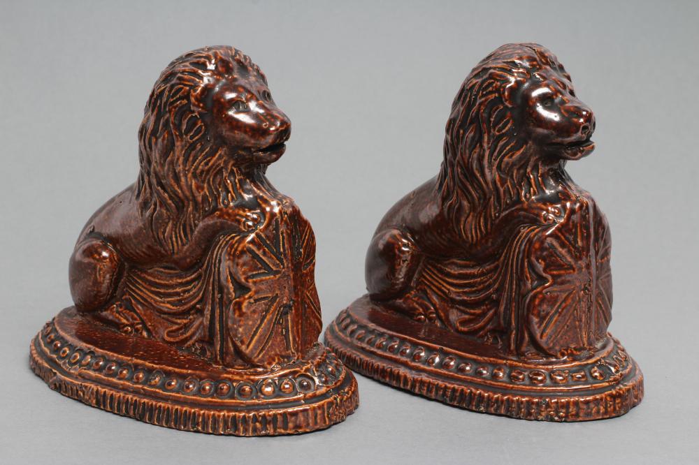 A PAIR OF BRAMPTON TYPE BROWN SALTGLAZE STONEWARE LIONS, early 19th century, modelled resting