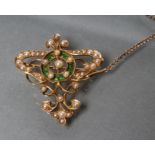 AN EDWARDIAN SEED PEARL PENDANT/BROOCH of open shield form centred by a circlet of green enamel,