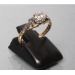 A SOLITAIRE DIAMOND RING, the old cut stone illusion set to shaped shoulders and a plain 18ct gold