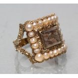 AN EARLY VICTORIAN MOURNING RING, the concave hair panel within a foliate chased border set with