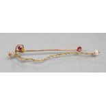 AN EDWARDIAN TIE PIN, the "S" scroll head claw set with a small facet cut ruby and old cut