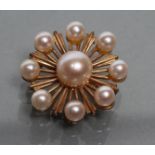 A 9CT GOLD STAR BROOCH, peg set with eight small cultured pearls around a central larger pearl,