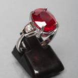 A RUBY RING, the oval facet cut glass filled stone of approximately 7.7cts, claw set to shaped