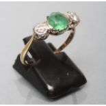 AN EMERALD AND DIAMOND THREE STONE RING, the circular facet cut emerald claw set and flanked by