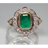 AN EMERALD AND DIAMOND ART DECO STYLE DRESS RING, the central oblong cut stone collet set to a lobed