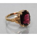 A VICTORIAN GARNET RING, the oblong cut stone claw set to leafy shoulders and a plain shank, stamped