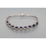 A SYNTHETIC SAPPHIRE AND DIAMOND BRACELET, the nine clusters set to an unmarked white gold oblong