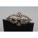A VICTORIAN DIAMOND BROOCH, the two open heart shaped panels set with old mix cut stones centred