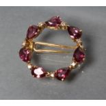 AN 18CT GOLD WREATH BROOCH/PIN, claw set with seven facet cut tear shaped garnets with diamond