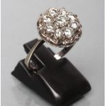 A NINE STONE DIAMOND CLUSTER RING, the round brilliants point and open set to a flower border and